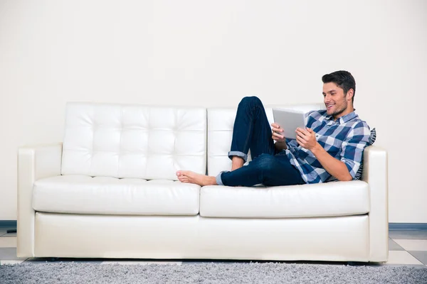 Homme couché sur le canapé avec tablette — Photo