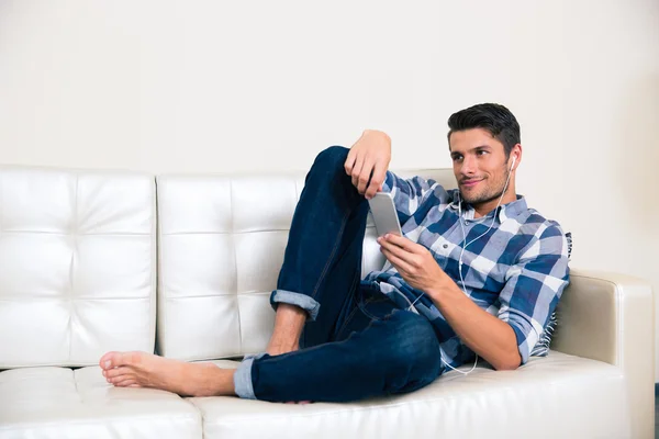 Homem deitado no sofá e usando smartphone — Fotografia de Stock