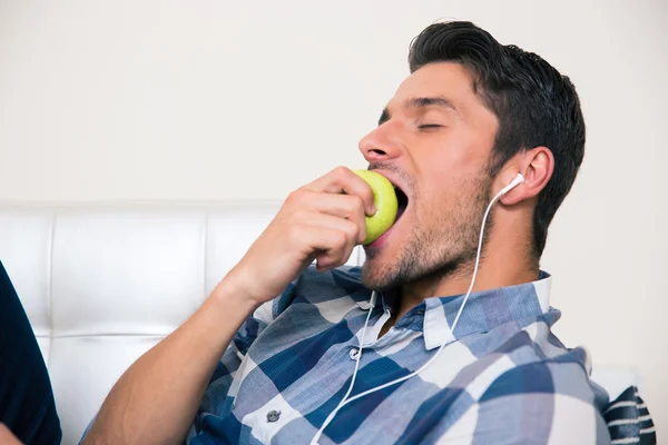 Hombre comiendo manzana en el sofá — Foto de Stock