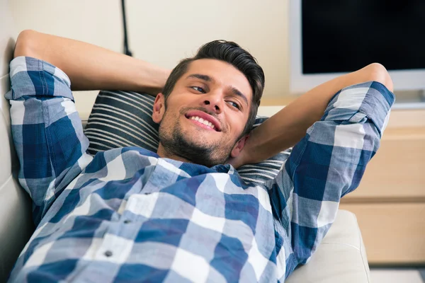 Uomo sorridente appoggiato sul divano — Foto Stock