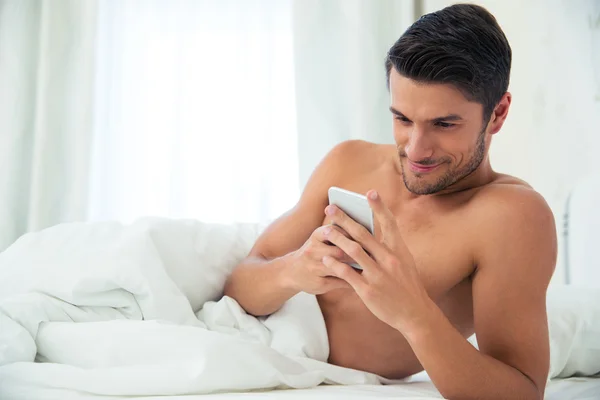 Homme utilisant smartphone sur le lit — Photo