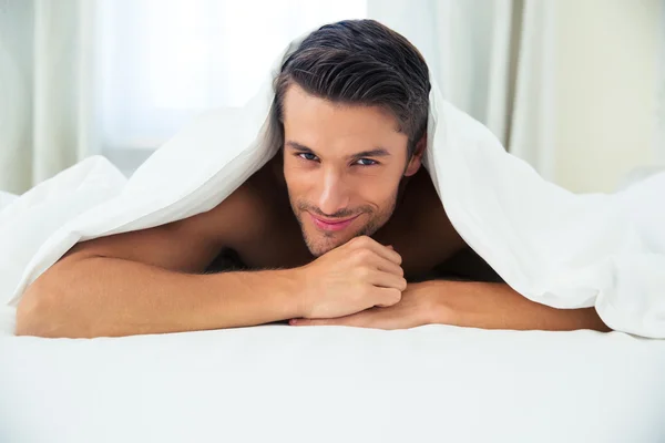 Homem deitado debaixo do cobertor na cama — Fotografia de Stock