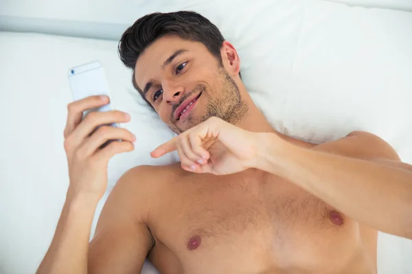 Чоловік використовує смартфон у ліжку — стокове фото