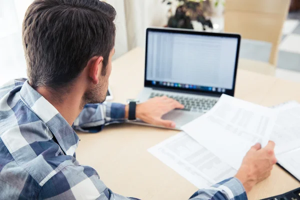 Mann sitzt mit Scheinen und Laptop am Tisch — Stockfoto