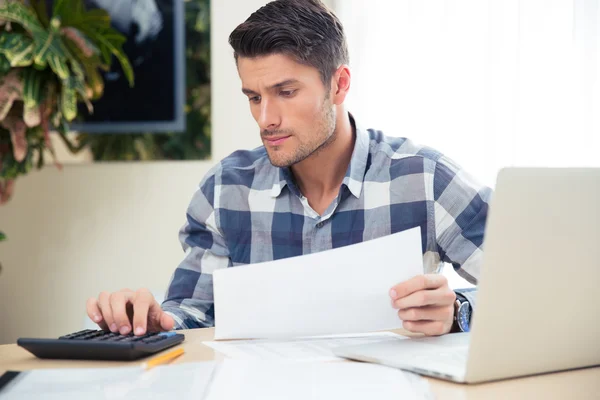 Man with calculator checking bills — Stock Photo, Image