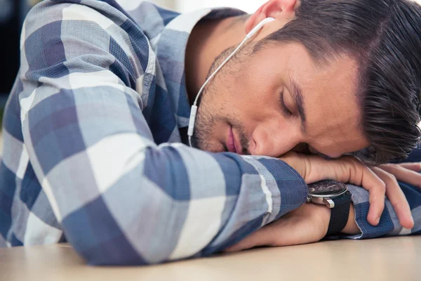 Hombre con auriculares durmiendo en la mesa —  Fotos de Stock