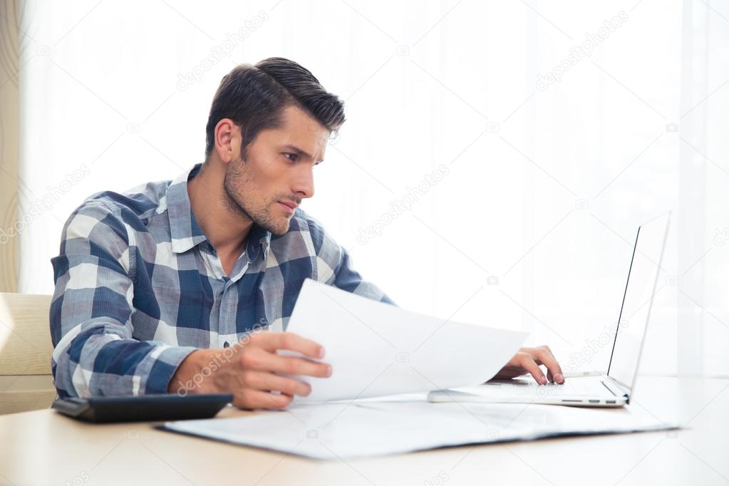 Man sitting at the table with bills and laptop