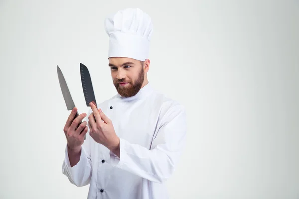 Cocinero sosteniendo y mirando cuchillos — Foto de Stock