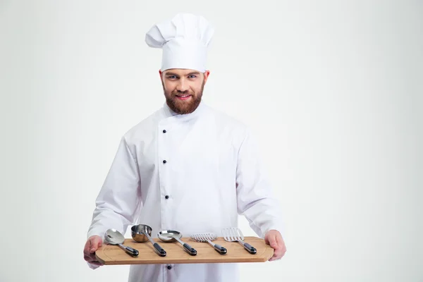 Chef cozinheiro segurando tábua de corte de madeira com colheres — Fotografia de Stock