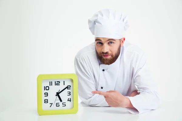 Chef-kok leunend op de tabel met klok — Stockfoto