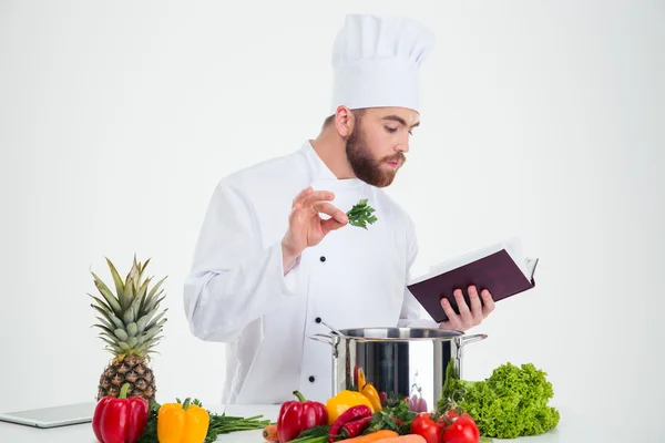 Male chef cook reading recipe book while preparing food — Stock Photo, Image