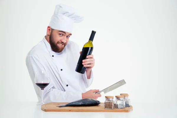 Cozinheiro chef masculino preparando peixe e segurando garrafa com vinho tinto — Fotografia de Stock