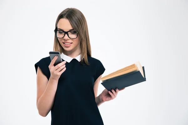 Smiling girl holding book and using smartphone — Stock Photo, Image