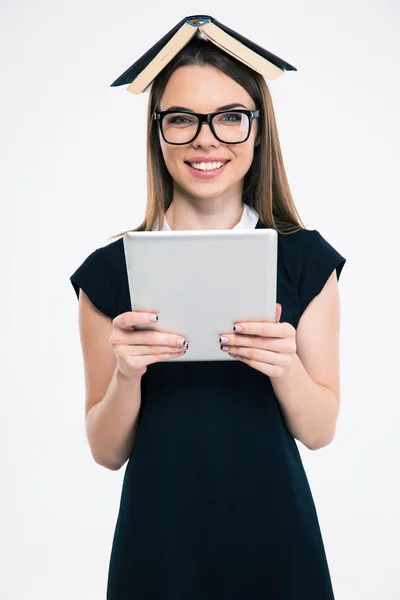 Smiling woman with book on head using tablet computer — Stock Photo, Image