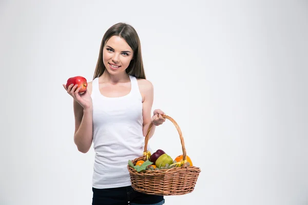 Chica sonriente sosteniendo cesta con frutas — Foto de Stock