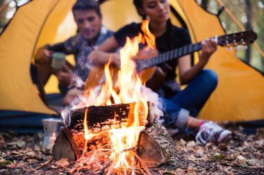 Şenlik ateşi yakınındaki gitar ile oturan Çift