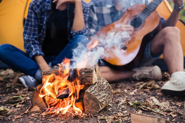 Paar sitzt mit Gitarre am Lagerfeuer im Wald — Stockfoto