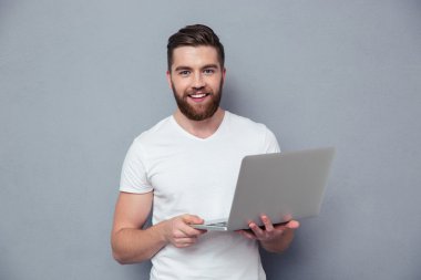 Dizüstü tutmak gülümseyen bir casual adam portresi