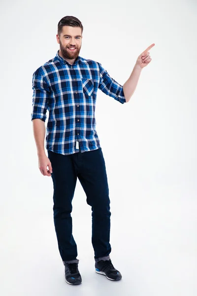 Full length portrait of a casual man pointing finger away — Stock Photo, Image