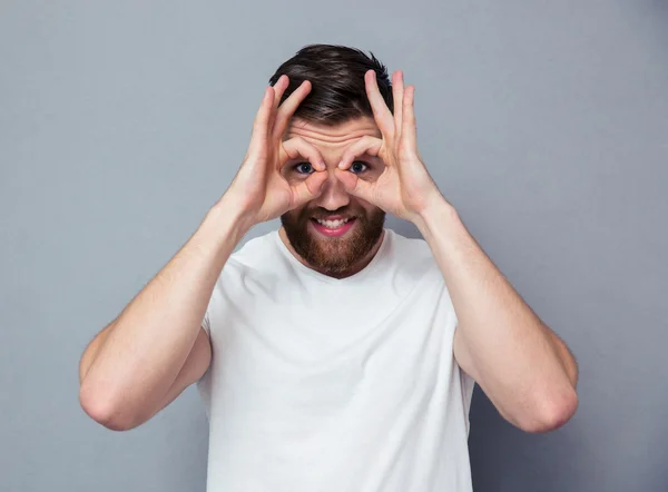 Happy man looking at camera through fingers — Stock Photo, Image