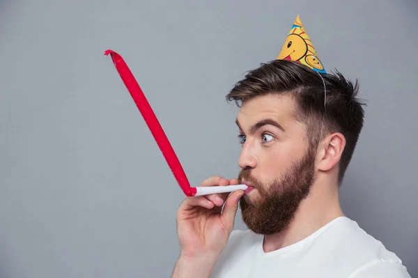 Человек в шляпе для вечеринок свистит в свисток — стоковое фото