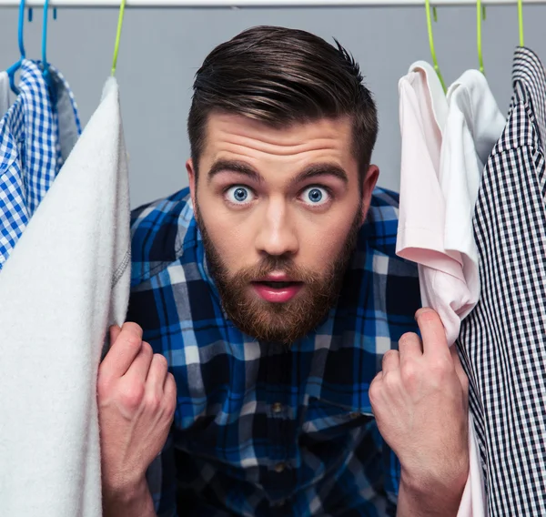 Förvånad hipster man standind nära rack med kläder — Stockfoto