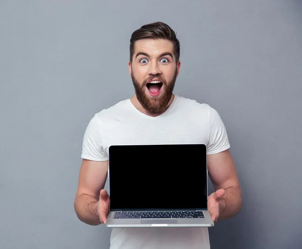 Hombre alegre mostrando la pantalla del ordenador portátil en blanco — Foto de Stock