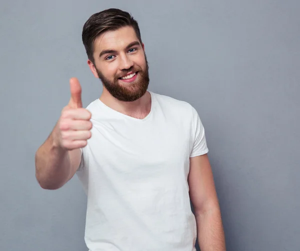 Lässiger Mann zeigt Daumen hoch und schielt auf Kamera — Stockfoto