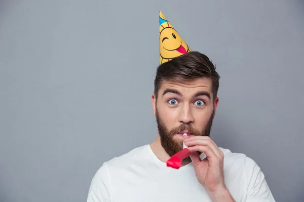 Bonito homem com chapéu de festa soprando no apito — Fotografia de Stock