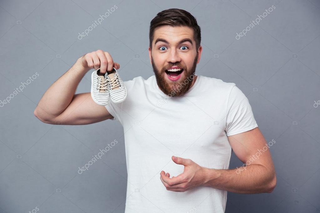 Laughing man holding small shoe