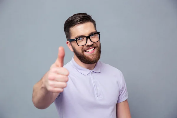 Homme souriant dans des lunettes montrant pouce vers le haut — Photo