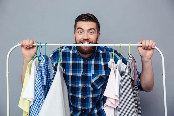 Happy hipster man står med rack av kläder — Stockfoto