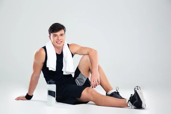 Smiling athletic man sitting on the floor — Stock Photo, Image