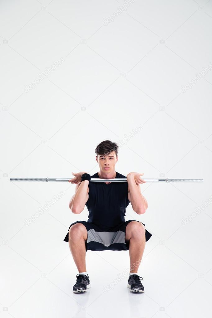 Athletic man doing squatting exercises with barbell