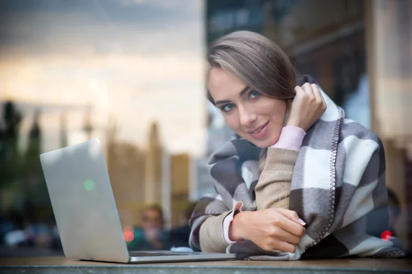 Lachende meisje zitten met laptop in café — Stockfoto