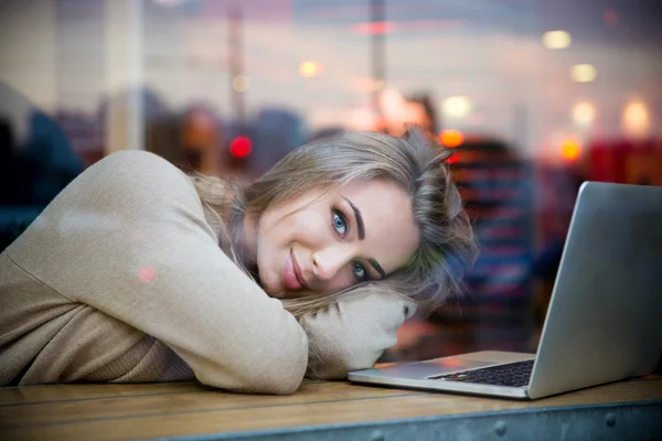 Cute girl lying on the table with laptop in cafe — Stock Photo, Image