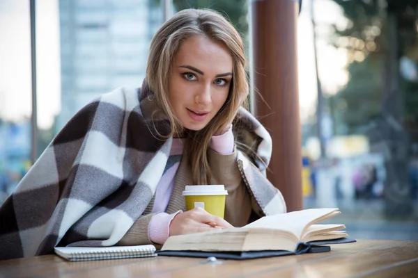 Portrait d'une fille heureuse assise avec un livre dans un café — Photo