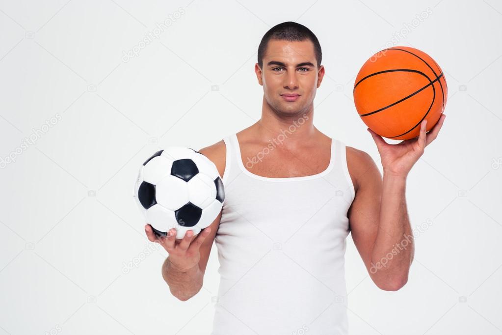 Handsome man holding basketball and soccer ball Stock Photo by