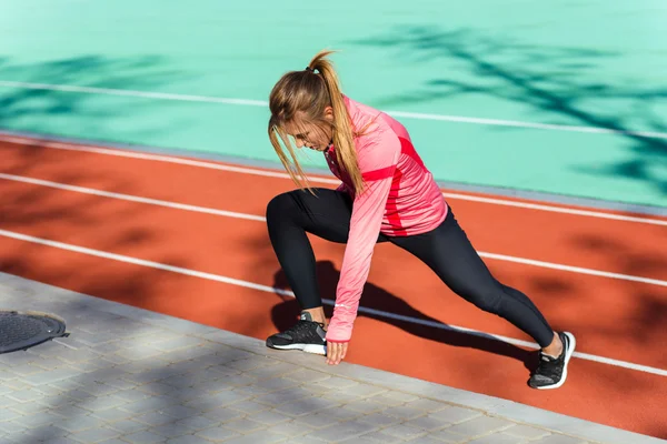 Kvinnan gör stretching övningar på stadium — Stockfoto