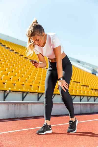 Mulher descansando após corrida e usando smartphone — Fotografia de Stock