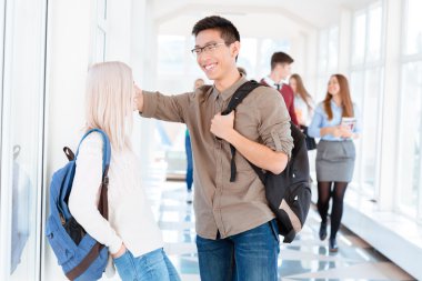 Asyalı çocuk ve sarışın kız koridorda konuşuyor