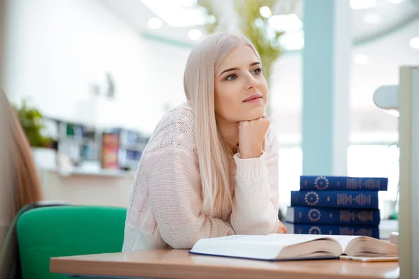 Портрет вдумчивой женщины с книгами в библиотеке — стоковое фото