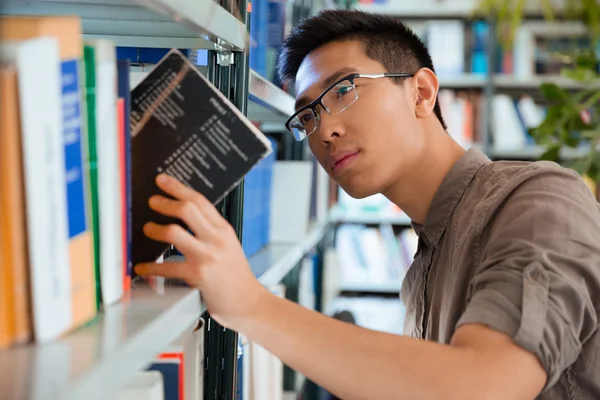 Homem procurando livro na biblioteca — Fotografia de Stock
