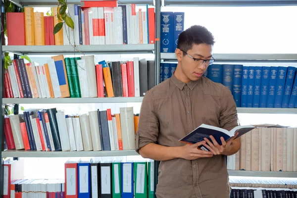 Homem leitura livro na biblioteca da universidade — Fotografia de Stock