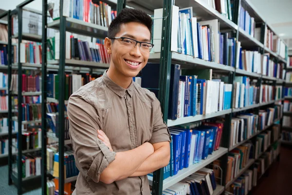 Man standing with arms folded in university library — Stock Photo, Image