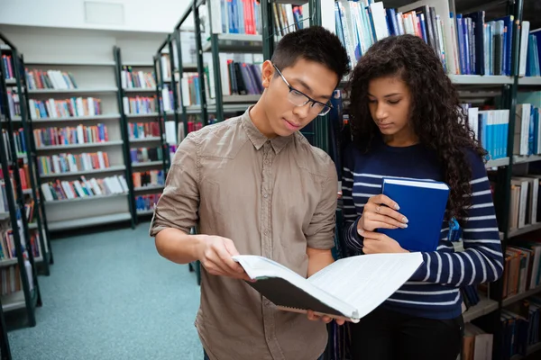 Students reading book in library — Stock Photo, Image