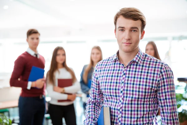 Mannelijke student permanent met klasgenoten op achtergrond — Stockfoto