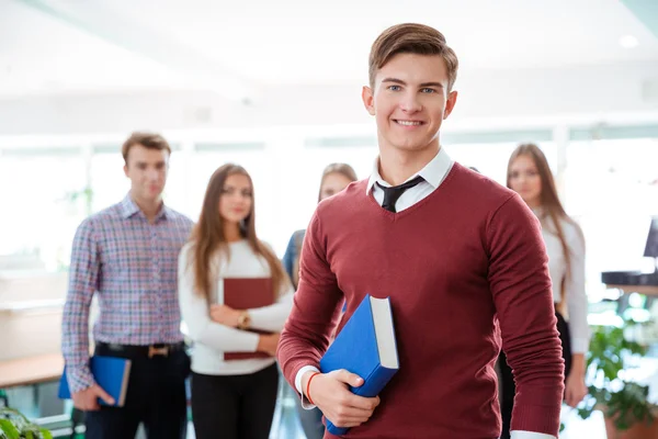 Manlig student står med klasskamrater på bakgrund — Stockfoto