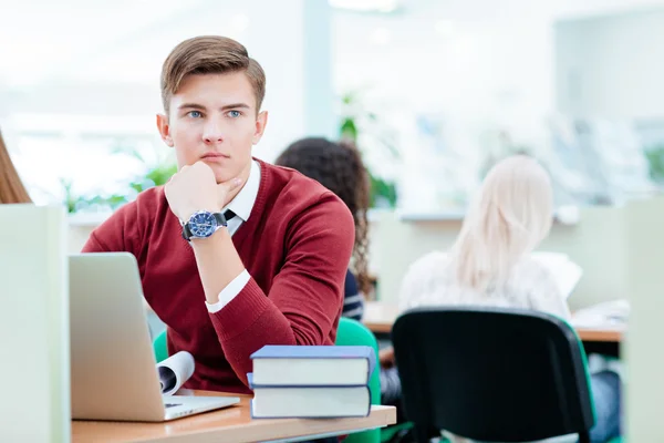 Estudiante masculino reflexivo sentado con computadora portátil —  Fotos de Stock