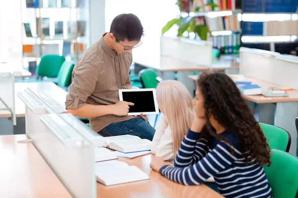 Man showing something on tablet computer to his classmates — Stock Photo, Image